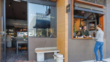 Un caffè dal design moderno, con un bancone, una zona con posti a sedere e una bacheca dei menu visibile dalla finestra.