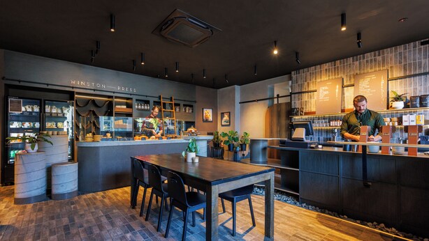 A modern restaurant interior with a bar area, seating, and a counter.