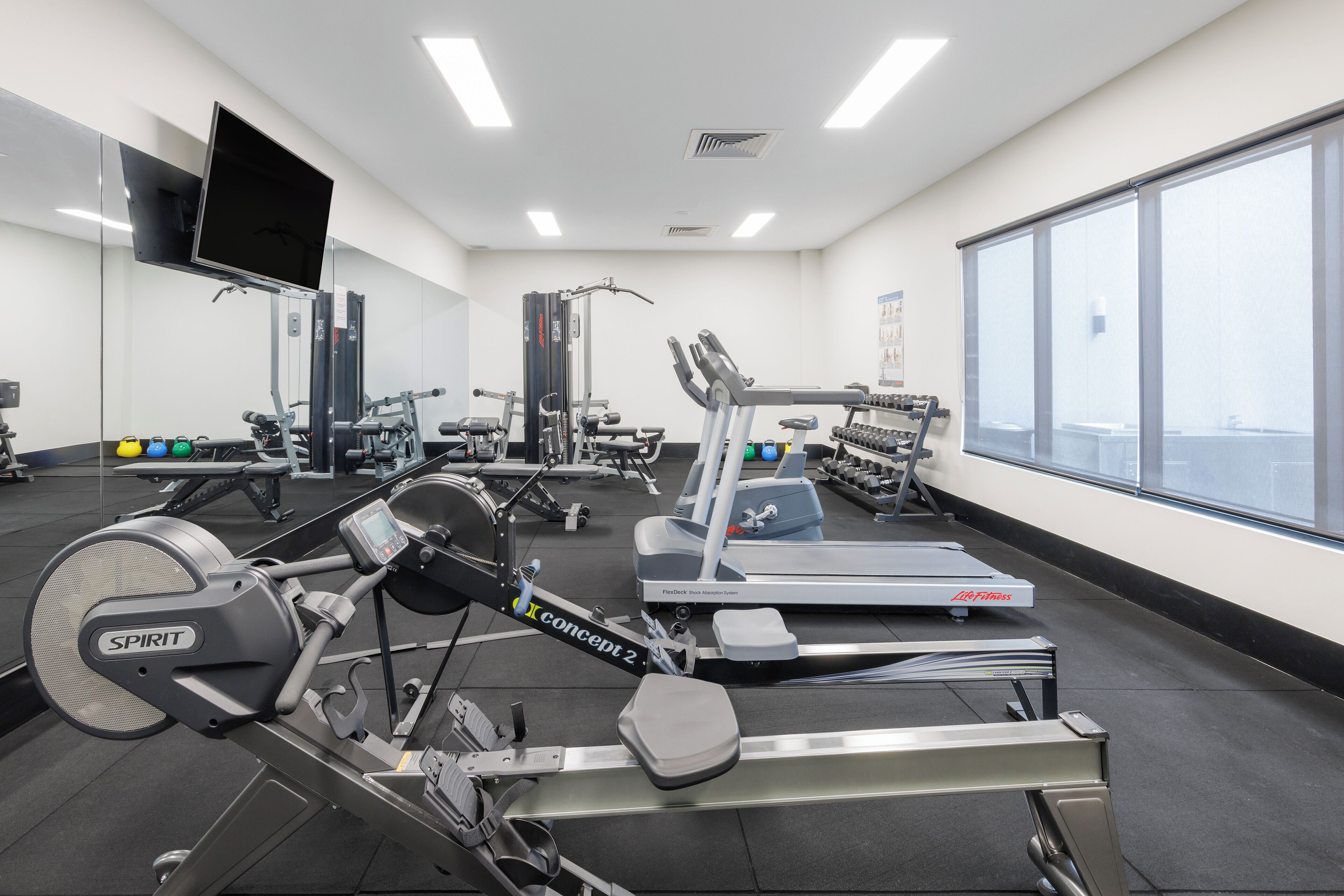 Une salle de sport équipée de machines de cardio, de matériel de musculation et dotée d’une grande fenêtre offrant une vue dégagée.