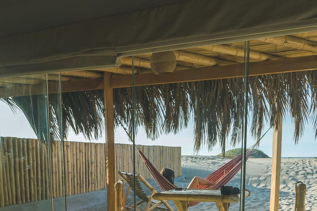 Une chambre située en bord de mer, avec un lit, un hamac et vue sur l’océan.
