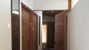 A hallway with wooden doors and a hanging light fixture. - Vistazul (Los Organos)