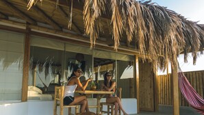 A wooden outdoor seating area with a thatched roof, a dog, and a hammock. - Vistazul (Los Organos)