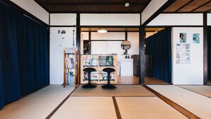 A traditional Japanese room with tatami flooring, a reception desk, and a bookshelf. - Hostel Dockhouse (Nagasaki)
