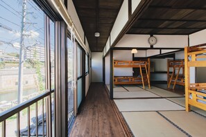 A traditional Japanese room with tatami flooring, wooden bunk beds, and a view of a river. - Hostel Dockhouse (Nagasaki)