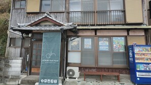 A traditional wooden building with a sign for KOKUBU Dock House, indicating it is a rest space and hostel for cyclists. - Hostel Dockhouse (Nagasaki)