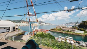 A view of a coastal area with a bridge, boats, and industrial buildings. - Hostel Dockhouse (Nagasaki)
