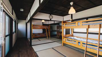 A traditional Japanese-style room with tatami flooring, wooden bunk beds, and a clock on the wall.
