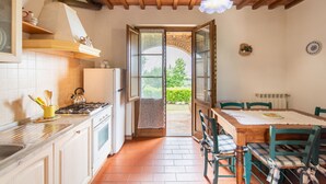 Une cuisine équipée d’une cuisinière, d’un réfrigérateur et d’une porte ouverte donnant sur un balcon.
