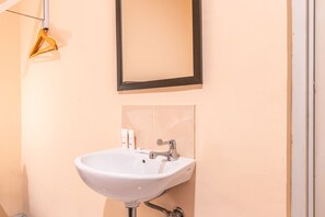 A bathroom with a white sink, a mirror, and a towel rack. - OYO 1554 Pavilio  Residence (Cikarang)