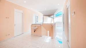 A hallway with a white door, a sink, and a staircase leading to an upper level. - OYO 1554 Pavilio  Residence (Cikarang)
