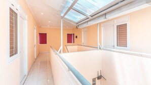 A corridor with a glass ceiling, white walls, and a tiled floor. - OYO 1554 Pavilio  Residence (Cikarang)
