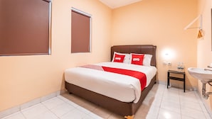 A hotel room with a bed, a bedside table with a water bottle, a sink, and a window with blinds. - OYO 1554 Pavilio  Residence (Cikarang)