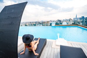 A poolside area with lounge chairs and a view of a city skyline. - M Suites by S Home (Ho Chi Minh City)