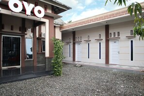A building with a prominent 'OYO' sign, multiple doorways, and a gravel pathway.