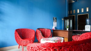 Una habitación con paredes azules, muebles de mimbre rojos, un mostrador de recepción de madera y un dispensador de agua.