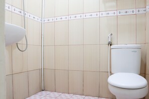 A bathroom with a toilet, a shower, and a sink. - OYO 2202 Delima Guest House Syariah (Padang)