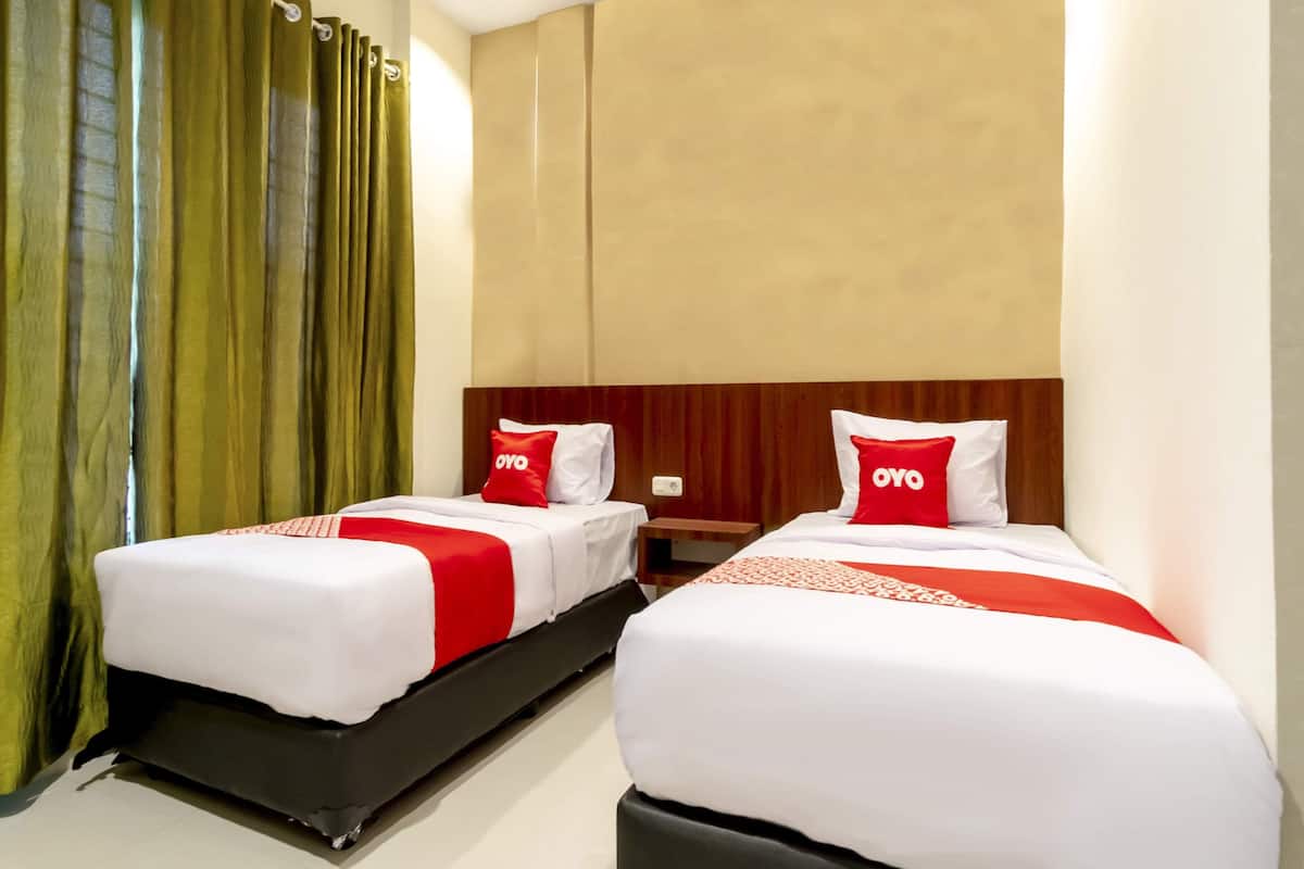 Two twin beds with red and white bedding, a wooden headboard, and a green curtain.