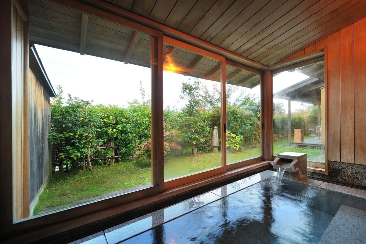 A hot tub area with a view of a garden through large windows.