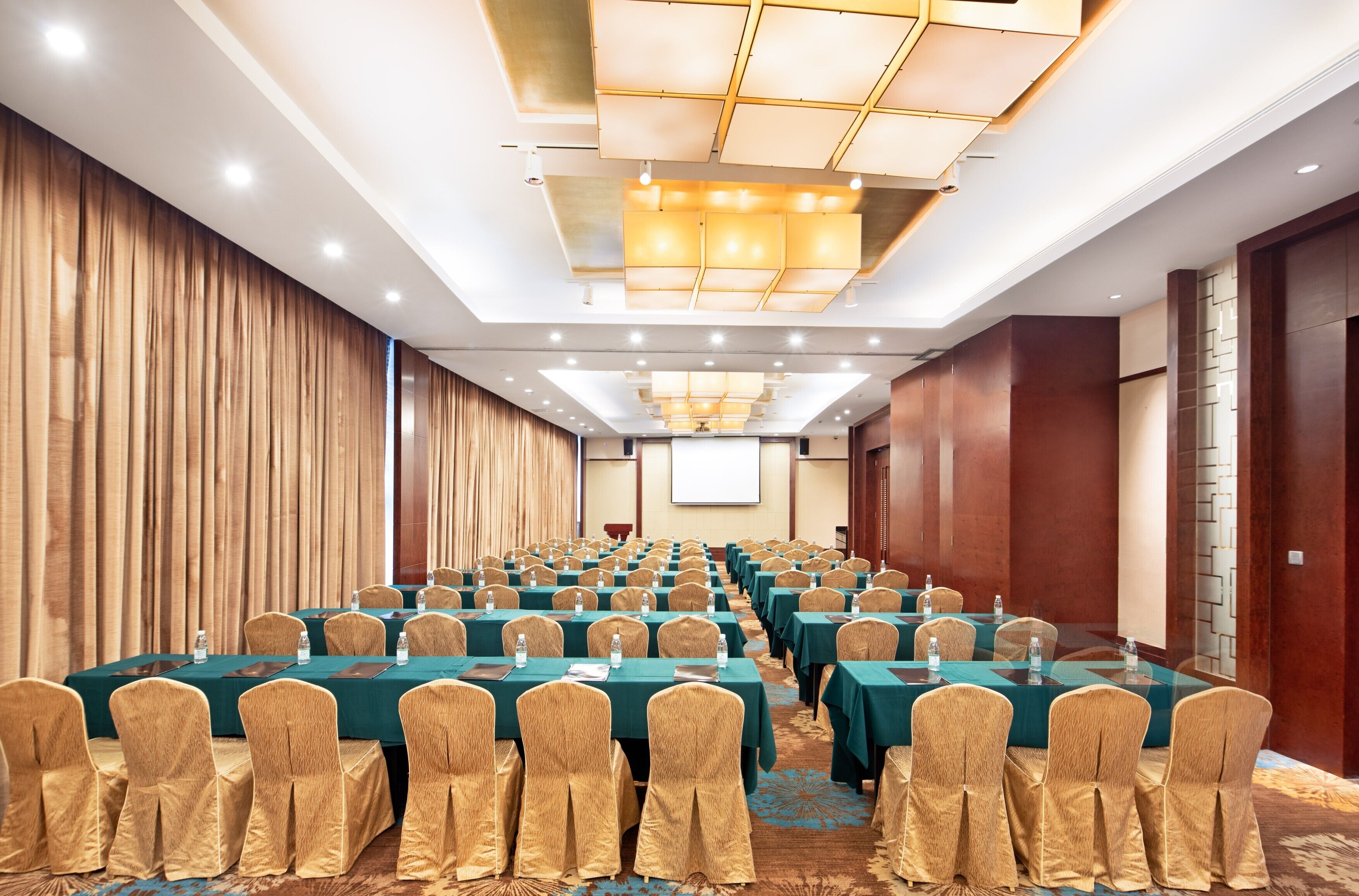 A conference room with rows of tables and chairs, equipped with water bottles and nameplates.