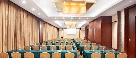 A conference room with rows of tables and chairs, equipped with water bottles and nameplates.