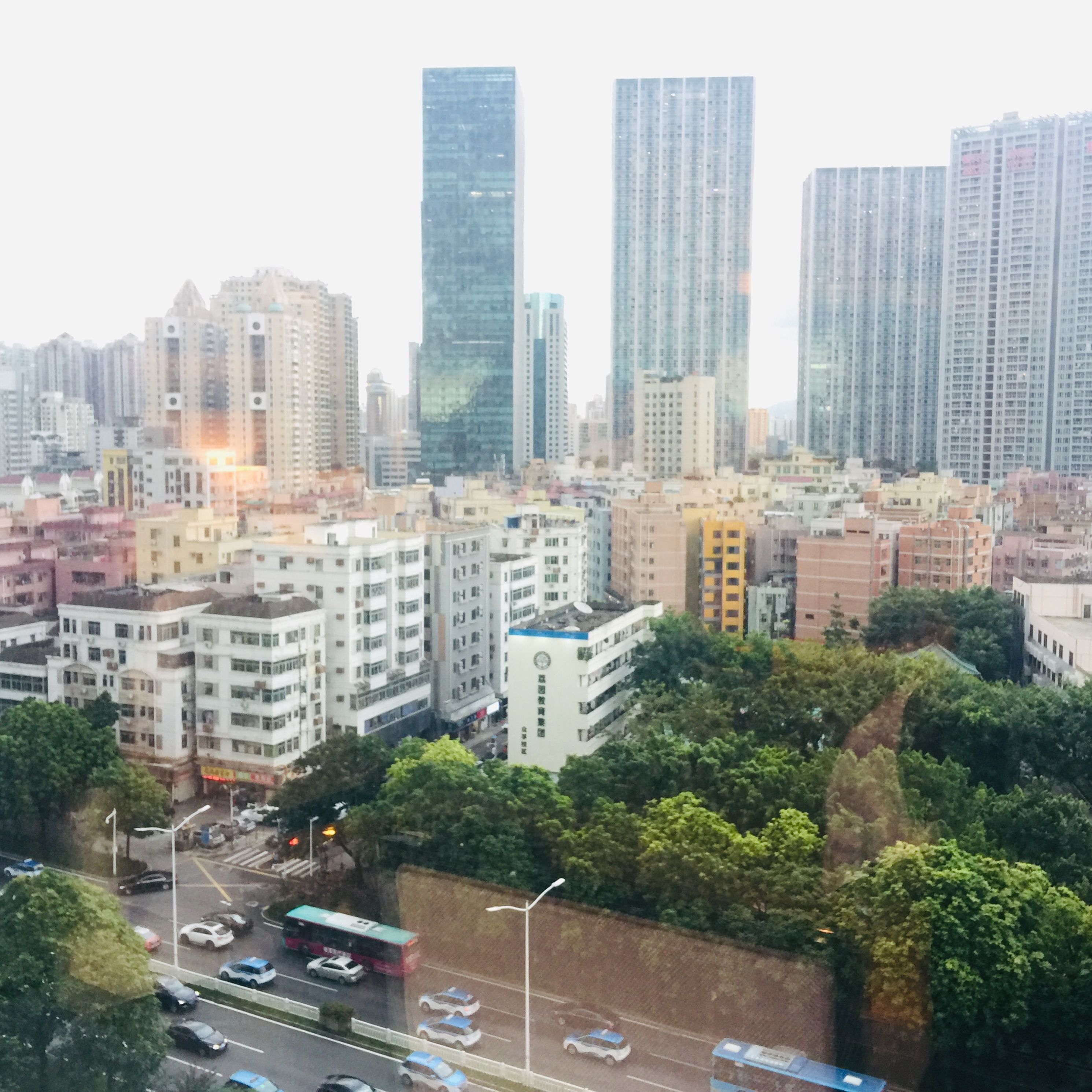 A cityscape with high-rise buildings, a mix of residential and commercial structures, and a road with vehicles.
