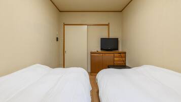 Habitación de hotel con dos camas individuales, un aparador de madera con televisor, y una puerta que da a otra habitación.