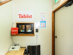 A room with a sign reading "Tabist," a telephone, a window with blinds, and some posted notices. - Tabist Tatsumi Business Hotel Matsusaka (Matsusaka)