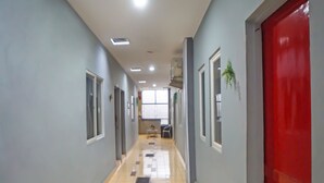 A hallway with a tiled floor, grey walls, and a red door on the right. - OYO 990 Stadion Residence Syariah (Medan)