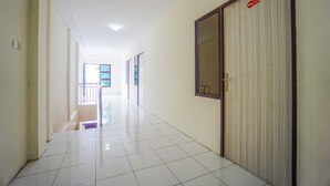 A corridor with tiled flooring, a door with a window, and a sign on the wall. - Super OYO 1838 COZY Home (Manado)