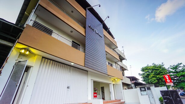 A multi-story building with a prominent 'coyhome' sign, a gated entrance, and a visible 'OYO' sign indicating a nearby OYO hotel. - Super OYO 1838 COZY Home (Manado)