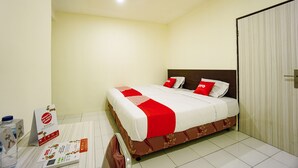 A neatly made bed with a red and white bedspread, a wooden headboard, and a white wall with a door to the right. - Super OYO 1838 COZY Home (Manado)