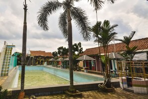 Una piscina rodeada de palmeras y edificios con tejados de tejas.
