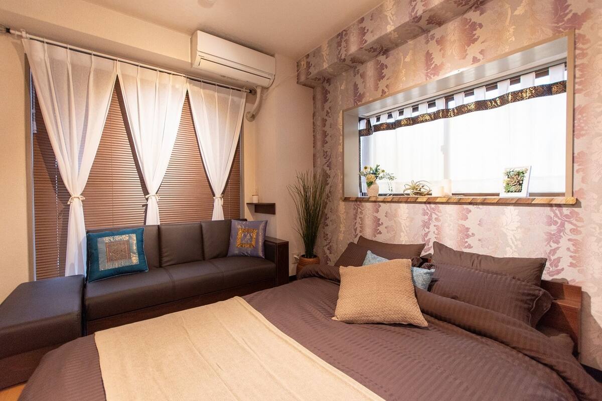 Un dormitorio con cama, sofá, ventana con vistas y equipo de aire acondicionado.