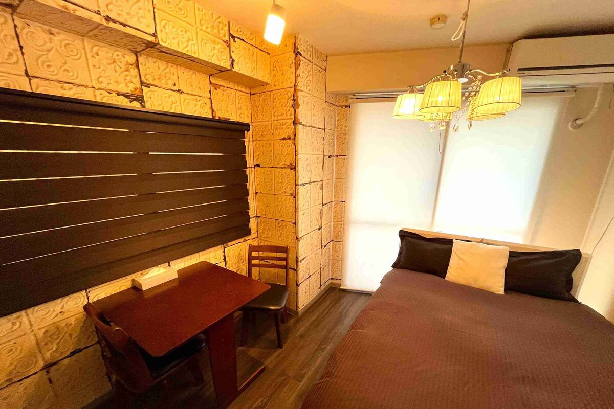 Un dormitorio con cama, escritorio, silla y ventana con cortinas.