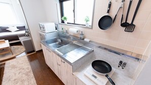 A compact kitchen with a built-in microwave, a sink, and a stove. There are hanging utensils and a window with plants.