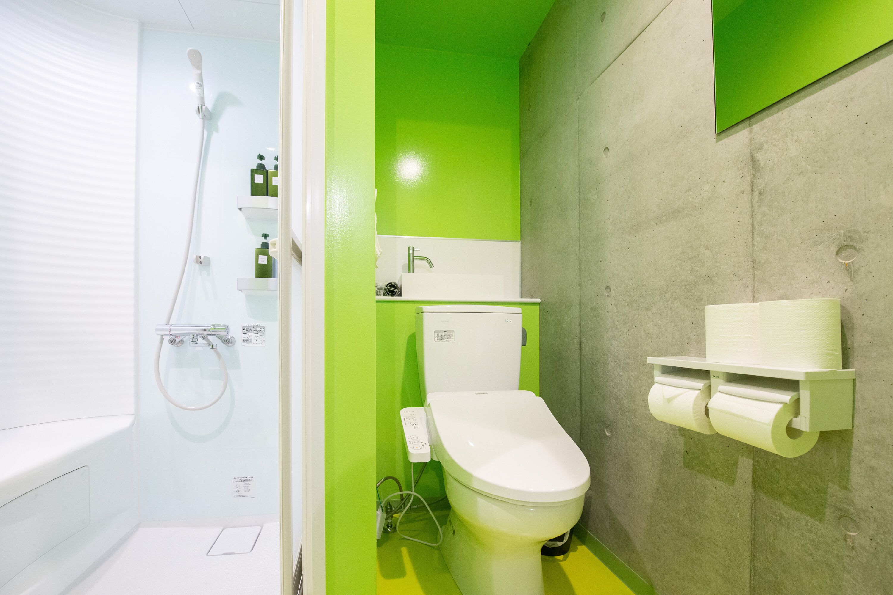 A bathroom with a toilet, a shower, and a toilet paper holder.