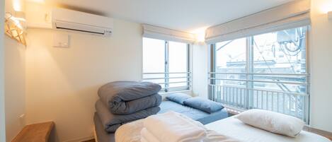 Una habitación de hotel con cama, un banco y una ventana con vista a un balcón.