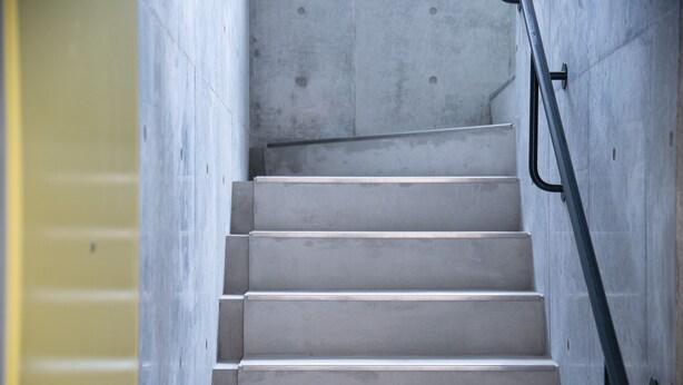 Eine Betontreppe mit Metallgeländern, die zu einer oberen Etage führt.