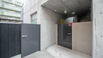 A narrow, enclosed corridor with concrete walls and a metal door.