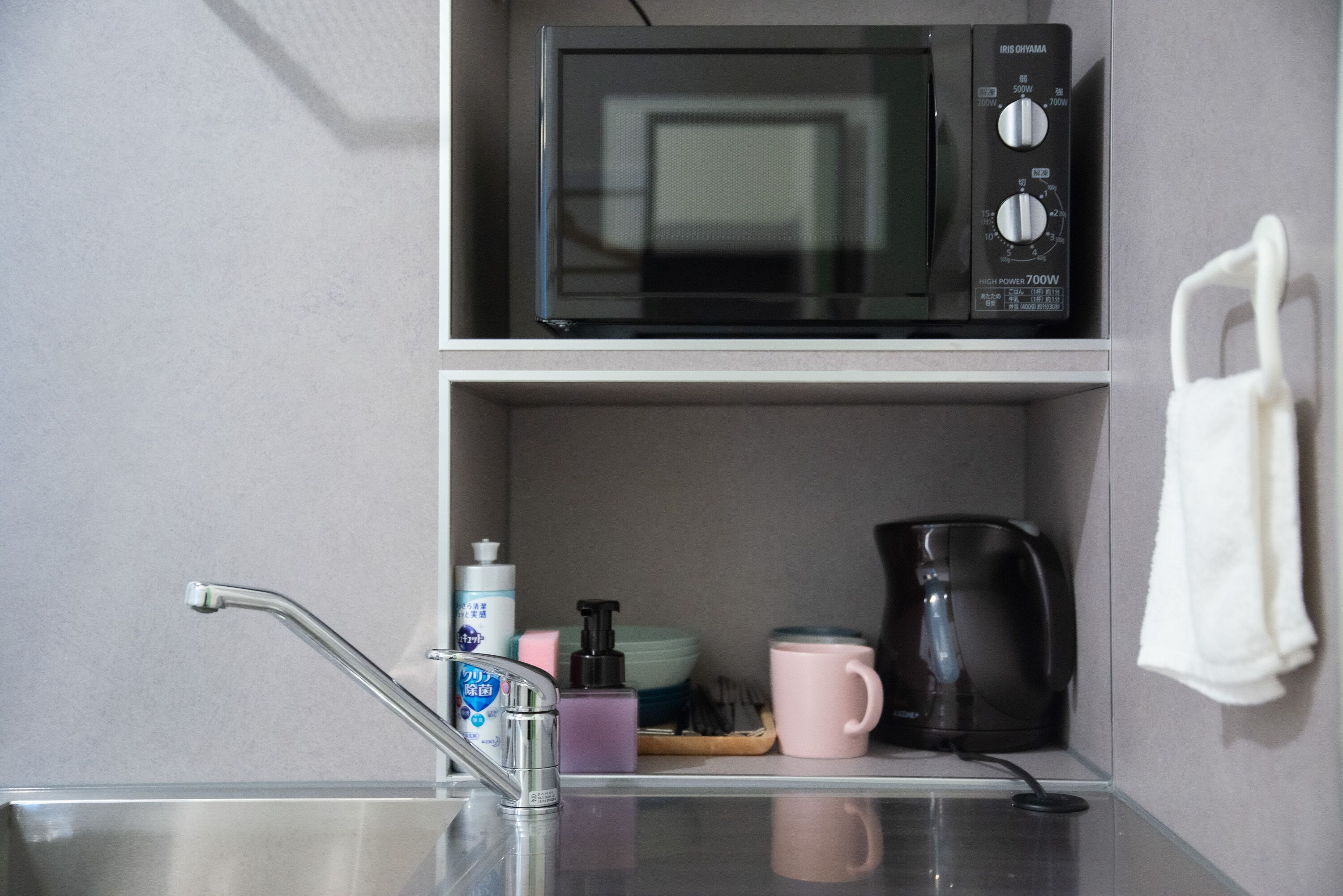 A kitchen with a microwave, coffee maker, and a sink with a faucet.