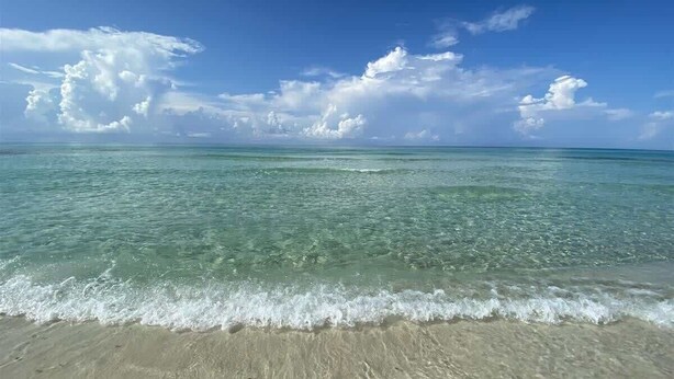 A beach with clear turquoise water, gentle waves, and a sandy shore under a blue sky with clouds. - Gulf and State Park Views, Private Beach, HOT TUB (Santa Rosa Beach)