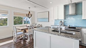 A modern kitchen with white cabinets, a granite countertop, and a blue backsplash. - Gulf and State Park Views, Private Beach, HOT TUB (Santa Rosa Beach)