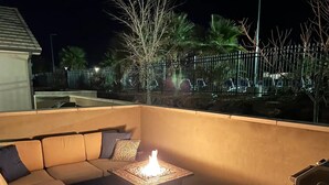 A cozy outdoor seating area with a cushioned sofa and a square table with a lit fire. - Poolside Adventures: FREE State and National Parks Passes! (Washington)