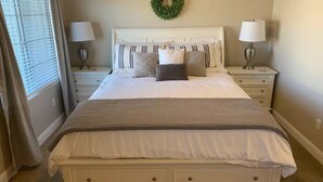 A neatly made bed with a white headboard, two bedside tables with lamps, a grey throw blanket, and a green wreath on the wall. - Poolside Adventures: FREE State and National Parks Passes! (Washington)
