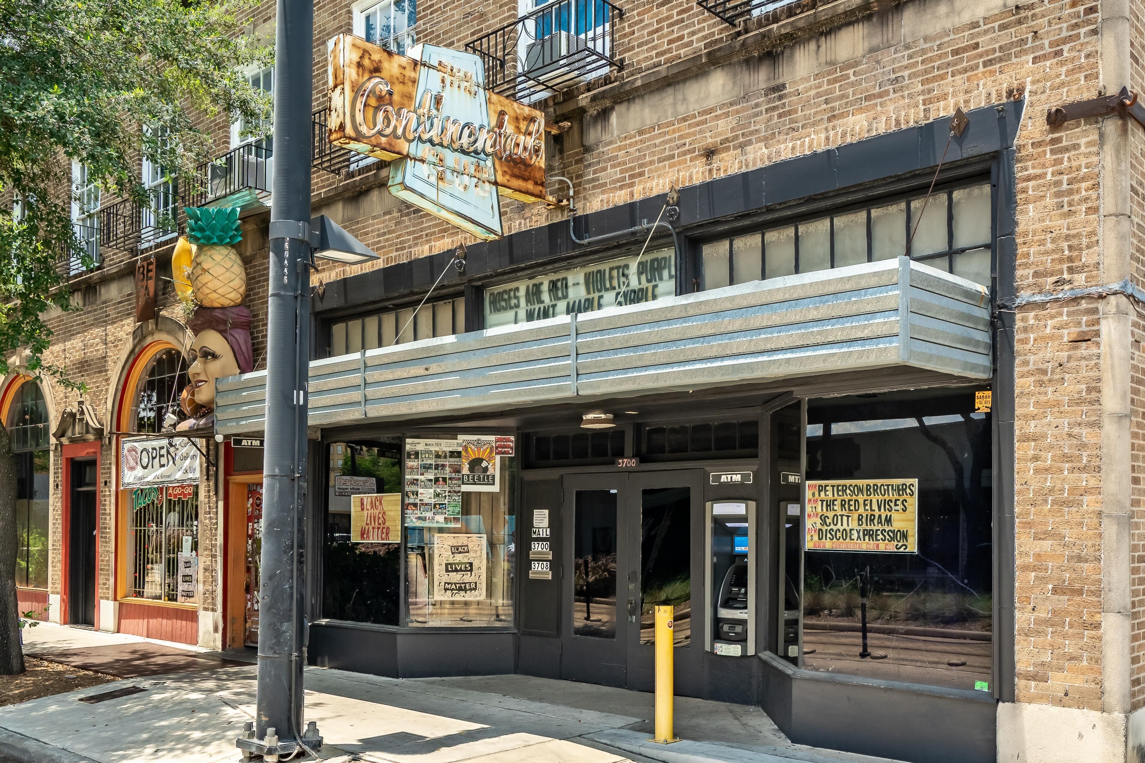 A theater with a marquee sign, a storefront with a 'Tacos' sign, and a 'Peterson Brothers' sign.