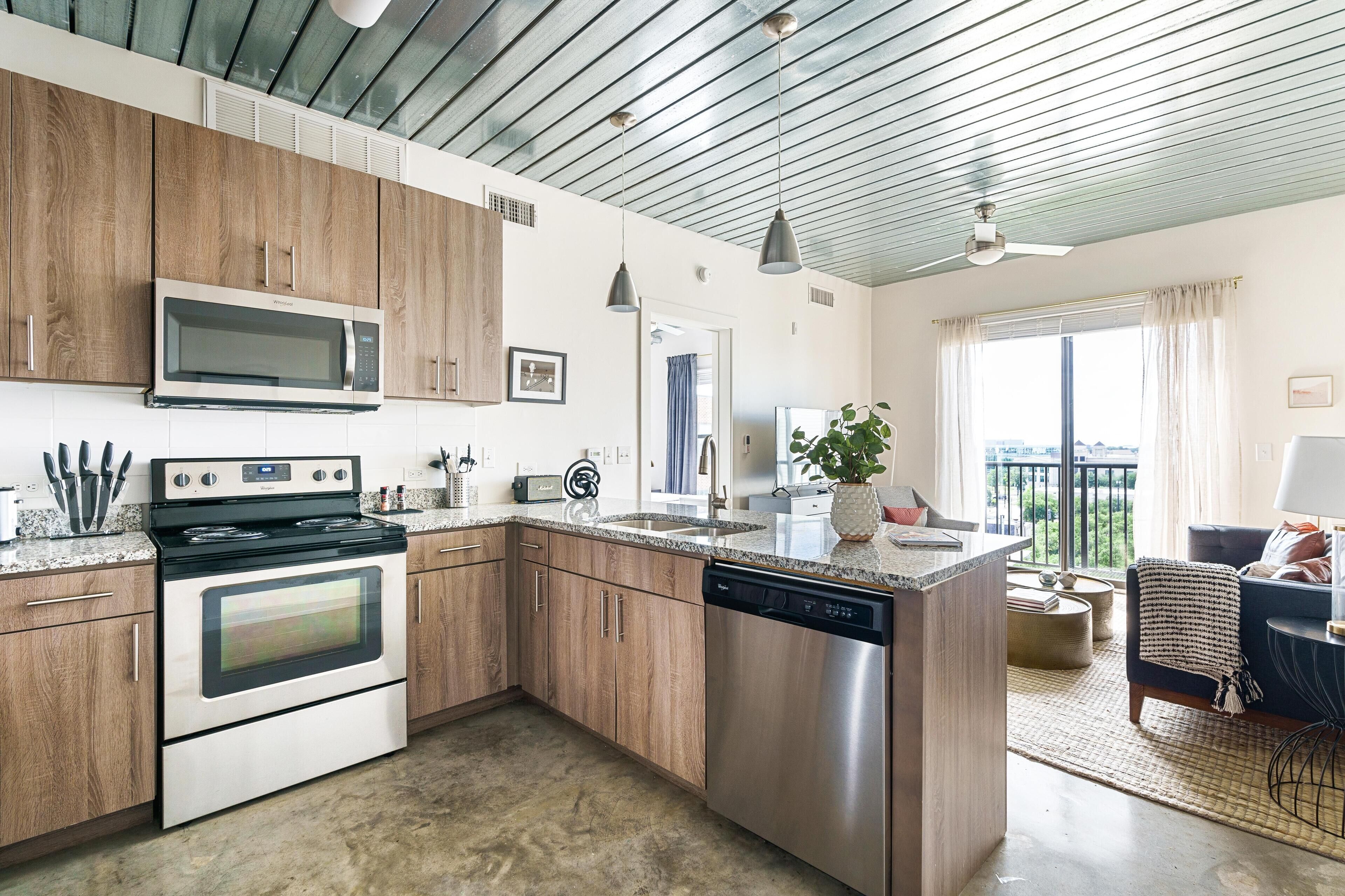 A modern kitchen with wooden cabinets, stainless steel appliances, and a large island.