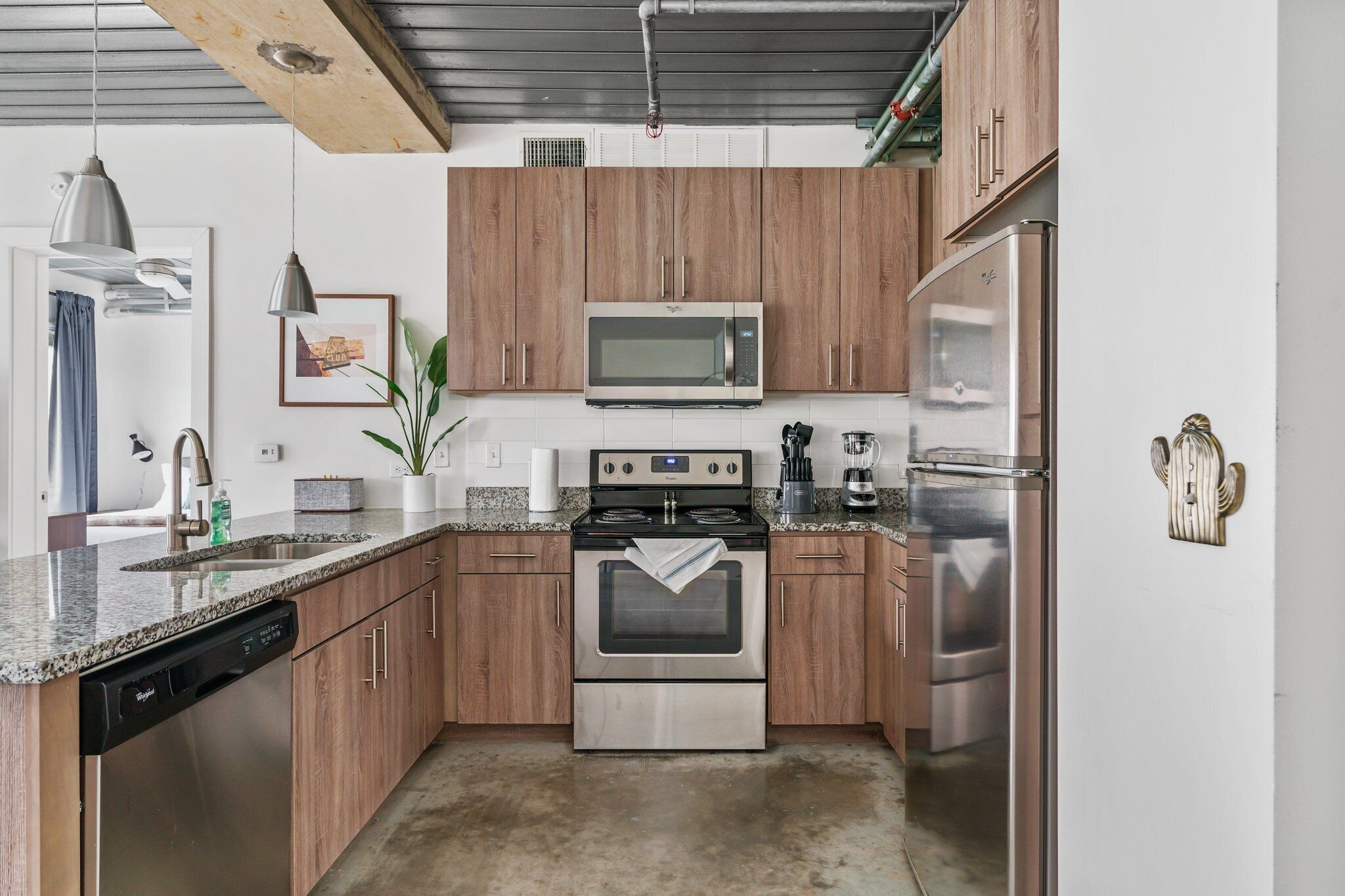 A modern kitchen with wooden cabinets, stainless steel appliances, a dishwasher, and granite countertops.