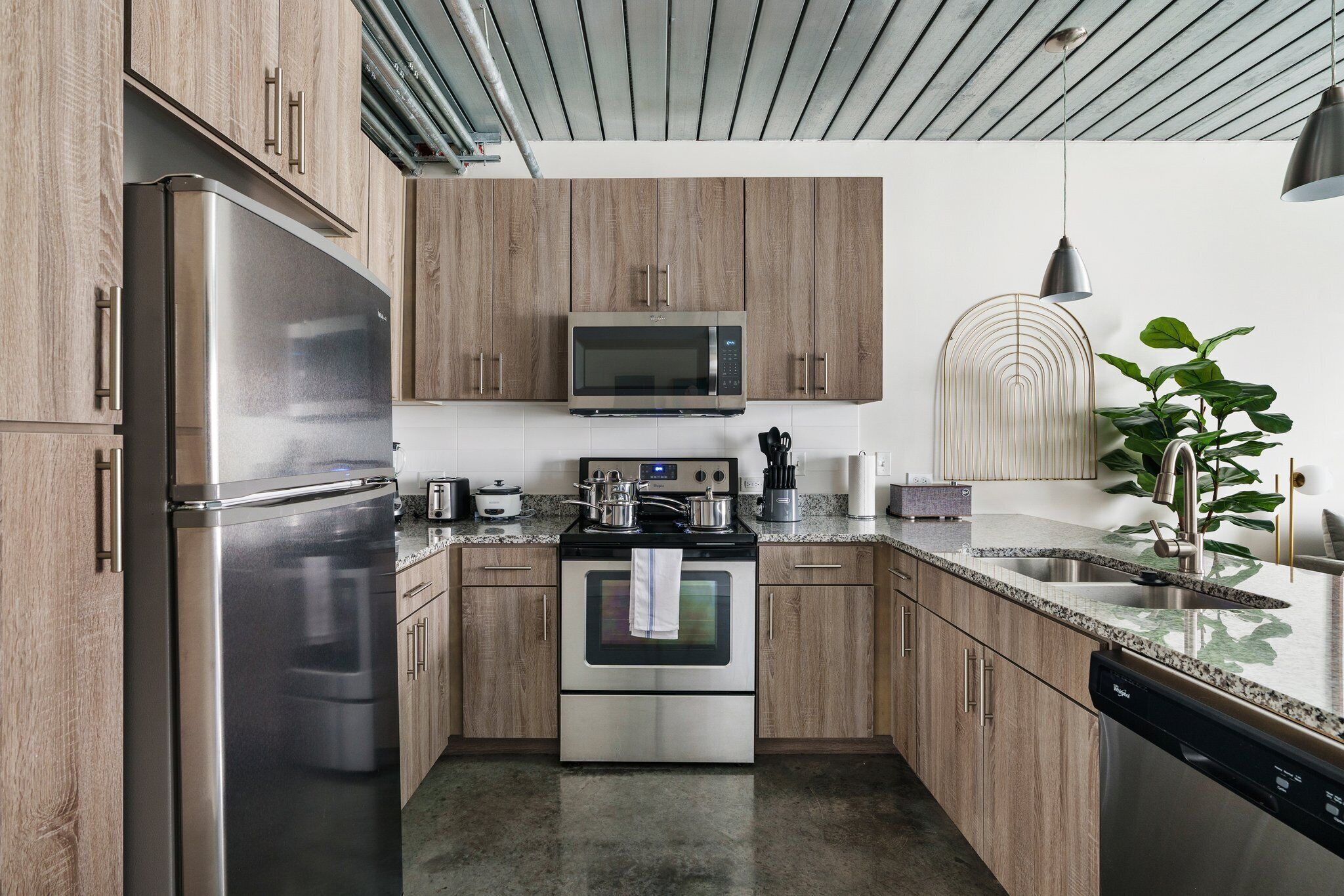 Une cuisine moderne dotée d’appareils électroménagers en acier inoxydable, d’armoires en bois et d’un plan de travail en granit.