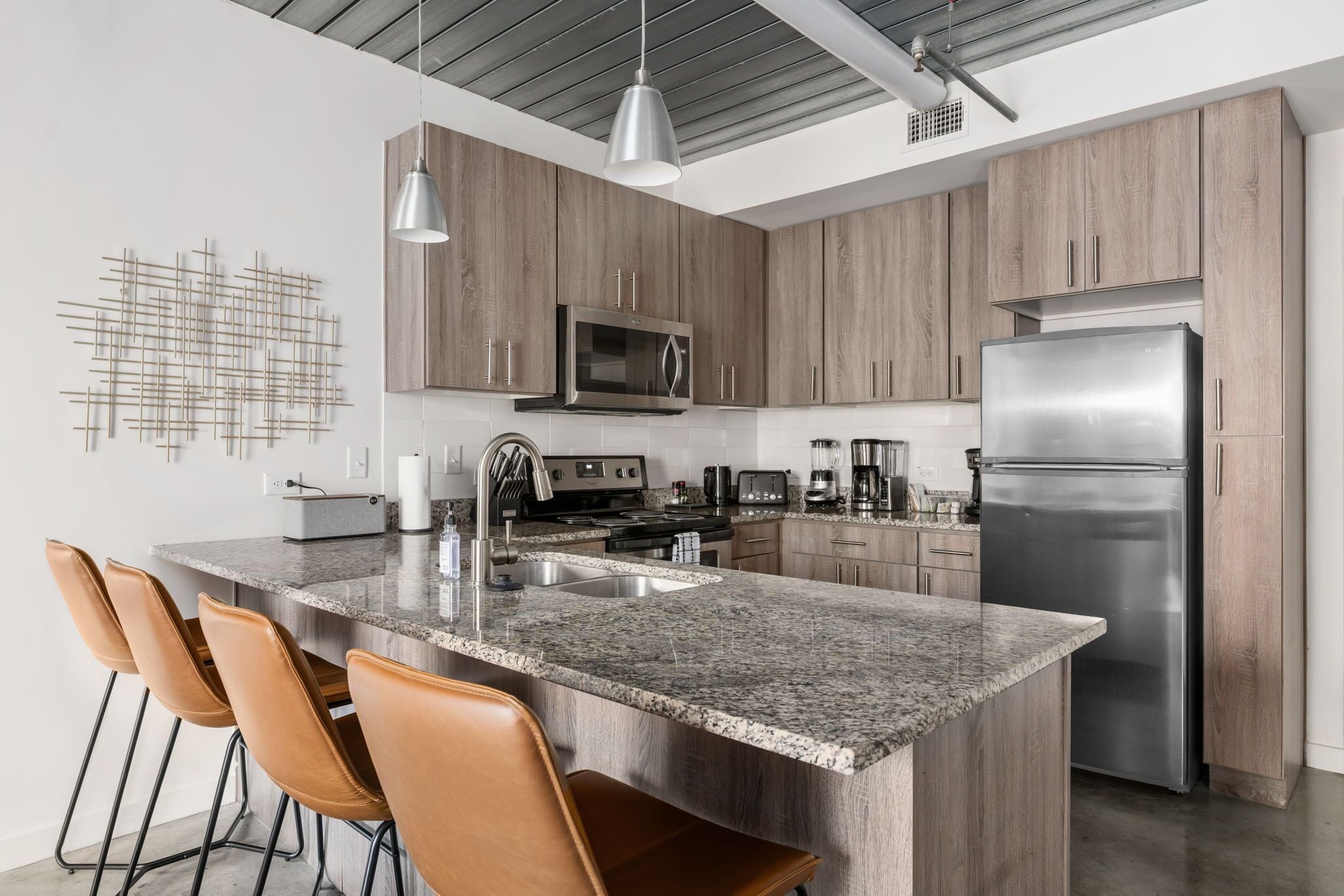 Una cocina moderna con encimeras de granito, electrodomésticos de acero inoxidable y armarios de madera.