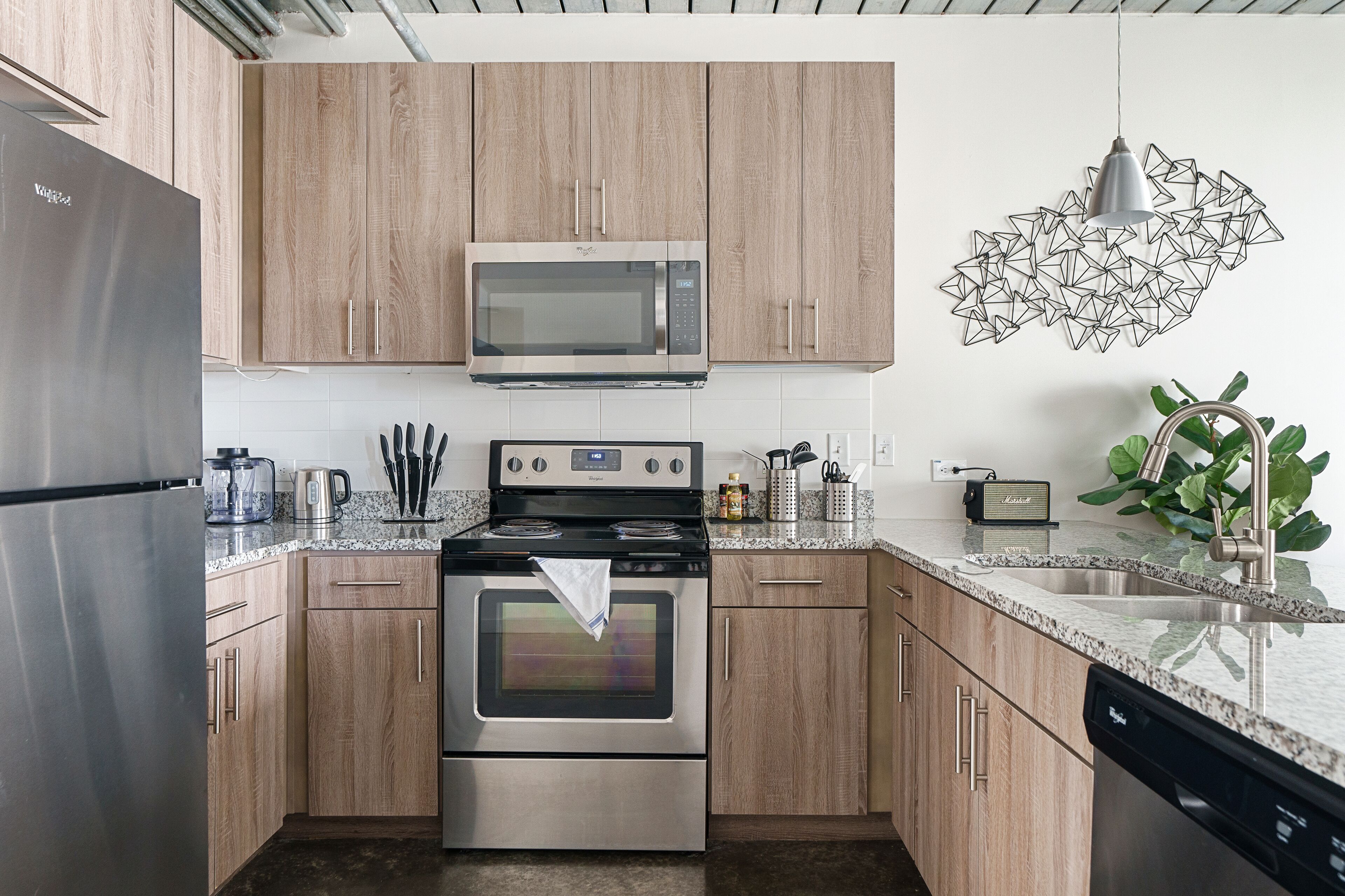 A modern kitchen with wooden cabinets, stainless steel appliances, and a granite countertop.